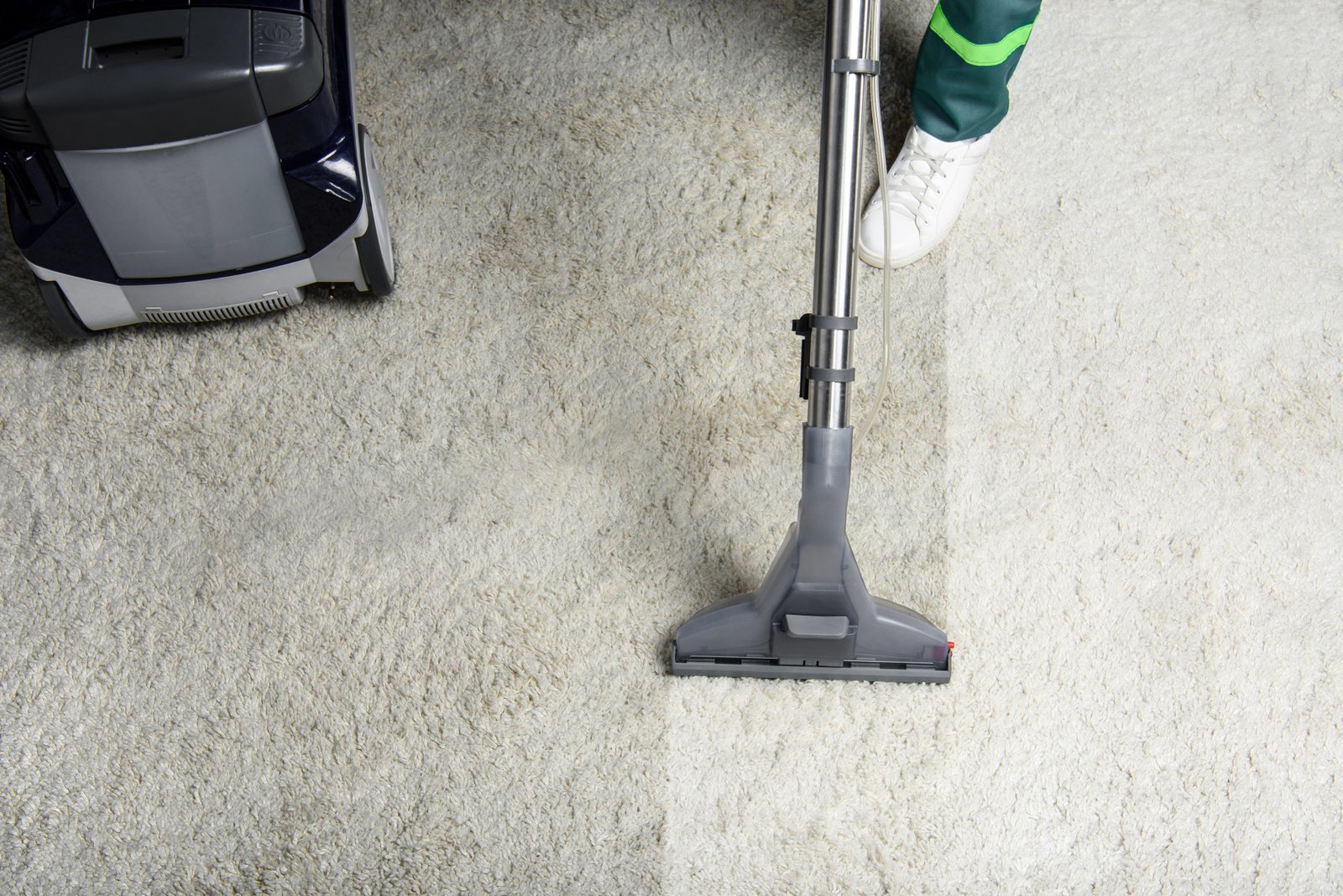 Home high angle view of person cleaning white carpet with professional vacuum cleaner